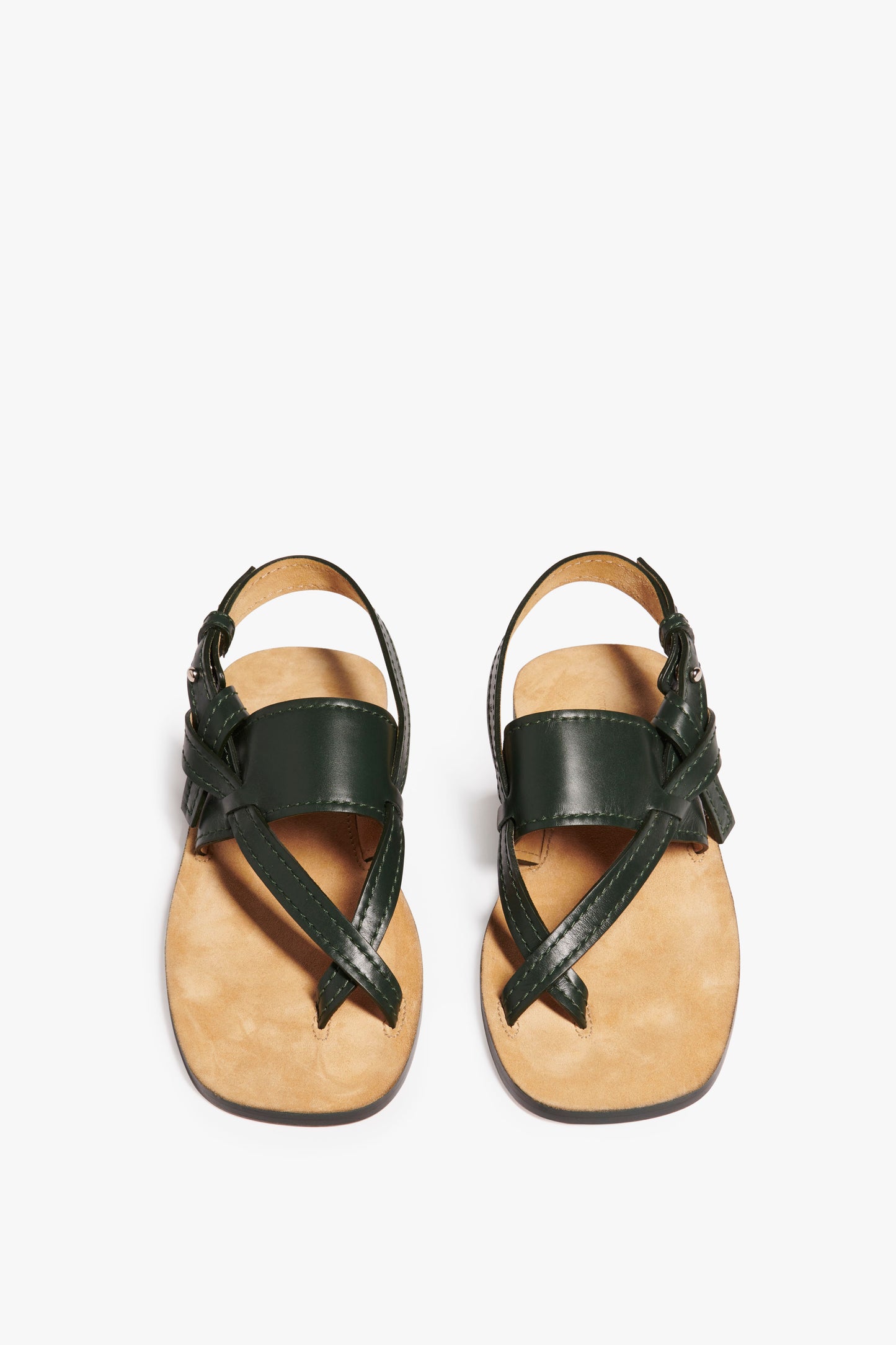 A pair of Victoria Beckham Eve Flat Sandal in Bottle Green with tan insoles and crossing straps is displayed on a white background.