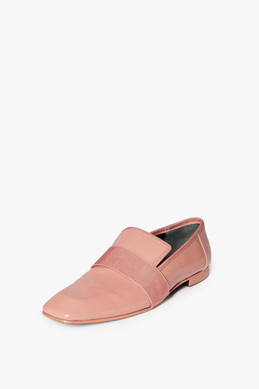 A single, rose-coloured patent leather Victoria Beckham Debbie Loafer in Rose with a glossy finish features a wide grosgrain band over the top, displayed on a plain white background.