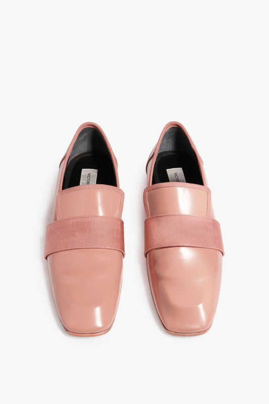 A pair of Victoria Beckham Debbie Loafer in Rose with glossy square toes and wide grosgrain band accents over the instep, viewed from above on a white background.