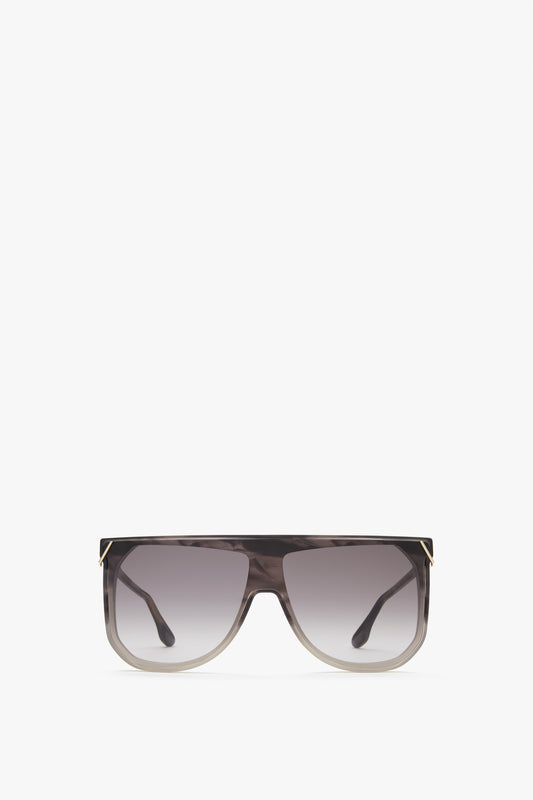 A pair of Classic Flat Top V Sunglasses in Striped Grey with a wide, striped grey frame. The sunglasses, part of the Victoria Beckham collection, feature gold accents on the top corners and temples.