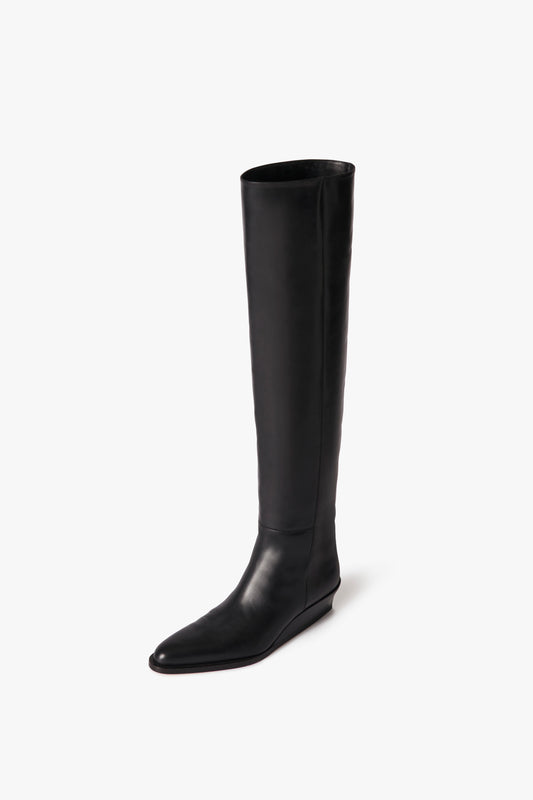 Fiona Boot In Black by Victoria Beckham crafted from stretch calf leather featuring a flat sole and a pointed toe, displayed on a white background.