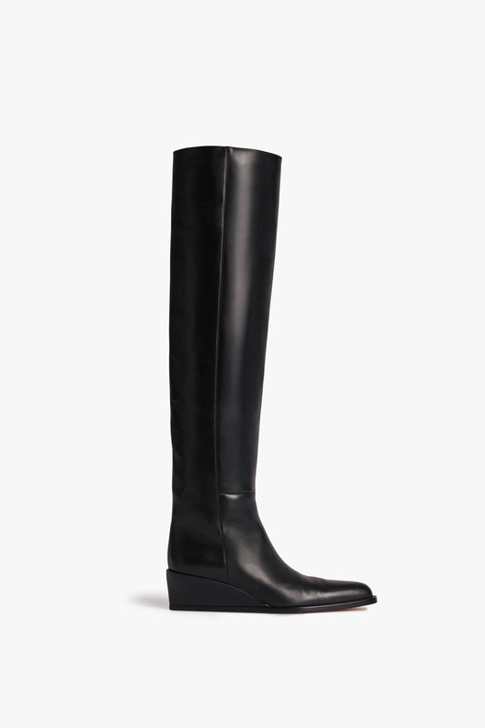 A black, knee-high leather boot with a low wedge heel, crafted from stretch calf leather, Fiona Boot In Black by Victoria Beckham, is shown against a white background.
