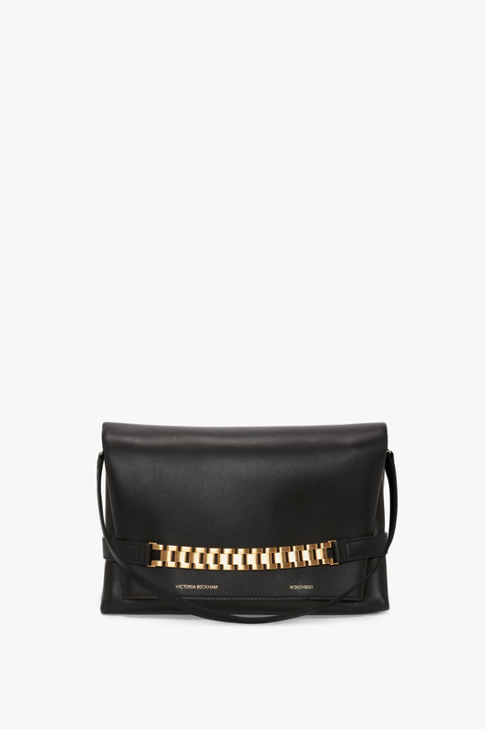 Victoria Beckham's Chain Pouch Bag with Strap In Black Leather features a gold-tone chain embellishment on the front and a detachable strap.