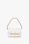 A Victoria Beckham Mini Chain Pouch Bag In White Leather crafted from Nappa leather with a short brown strap, a gold chain detail across the front, and featuring a detachable strap for versatile wear.