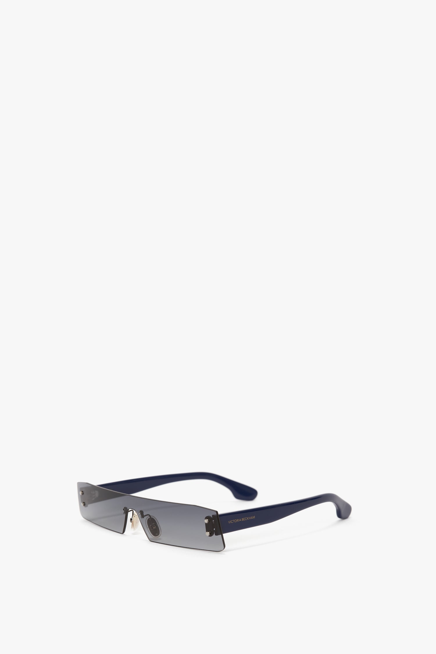 Mini Visor Sunglasses In Black-Green by Victoria Beckham, reminiscent of Victoria Beckham's SS23 collection, rest stylishly on a white surface.