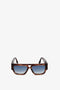 Square, Victoria Beckham V Plaque Frame Sunglasses In Dark Brown Horn with blue-tinted lenses on a plain white background.