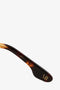 Close-up of a tortoiseshell eyeglass temple arm from the Victoria Beckham collection, featuring the letter "B" inscribed near the tip against a plain white background. These lightweight rectangle optical frames, known as Guilloche Frame Opticals In Dark Havana, are crafted in Dark Havana tortoise acetate, offering a blend of style and comfort.