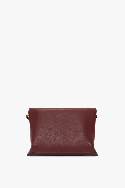 A Jumbo Chain Pouch Bag In Bordeaux by Victoria Beckham with a simple, rectangular shape, gold clasp, and clean lines, displayed against a white background.
