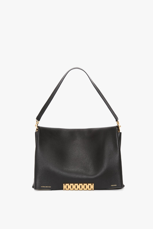 A Jumbo Chain Pouch Bag In Black Leather with a gold chain detail at the base, featuring a short handle for carrying, from Victoria Beckham.