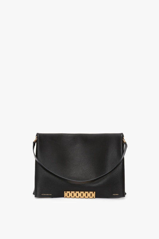 A Victoria Beckham Jumbo Chain Pouch Bag In Black Leather, featuring a gold chain detail on the front flap and a shoulder strap.