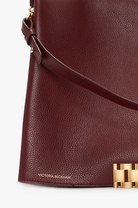 A close-up of a maroon grained leather handbag with a gold clasp and "Victoria Beckham" embossed in gold at the bottom, featuring a stylish detachable strap.

Replaced: A close-up of the Jumbo Chain Pouch Bag In Bordeaux with a gold clasp and "Victoria Beckham" embossed in gold at the bottom, featuring a stylish detachable strap.