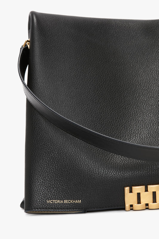 Close-up of a Jumbo Chain Pouch Bag In Black Leather with a gold clasp and the name "Victoria Beckham" in gold lettering on the bottom left corner.