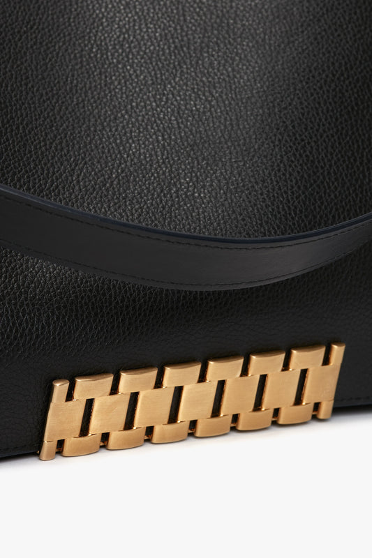 Close-up of a Jumbo Chain Pouch Bag In Black Leather by Victoria Beckham, featuring a gold chain-like embellishment near the bottom edge.
