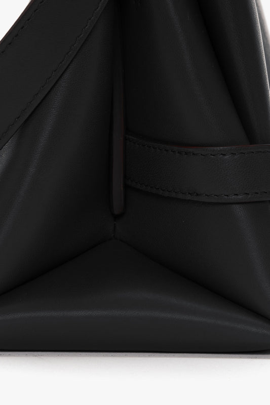 Close-up of a black Nappa leather Chain Pouch Bag with Strap In Black Leather by Victoria Beckham with stitched seams, featuring a folded and tacked design and a gold-tone chain detail.