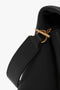 Close-up of a Victoria Beckham Chain Pouch Bag with Strap In Black Leather, showcasing the handle attached to a gold-tone ring.