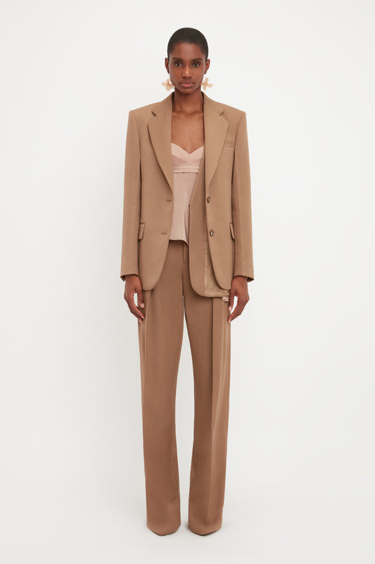 Model wears the asymmetric double layer jacket in fawn from designer Victoria Beckham. This brown blazer is single breasted and has a double layer detail.