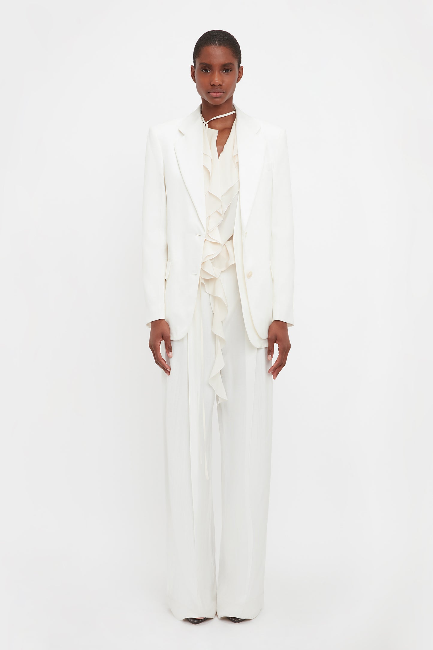 Model wears the asymmetric jacket in white from VB. This white blazer is a single breasted jacket with an asymmetric hemline and double layer detail. 