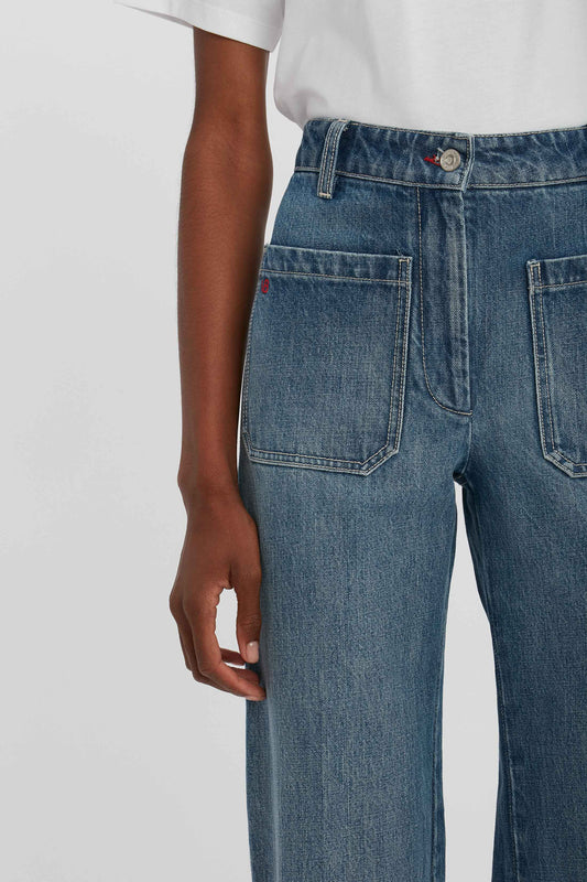 Close-up of an individual wearing high-waisted Victoria Beckham Alina High Waisted Jean In Shadow Wash with large front pockets and a white t-shirt, showcasing a classic denim silhouette.