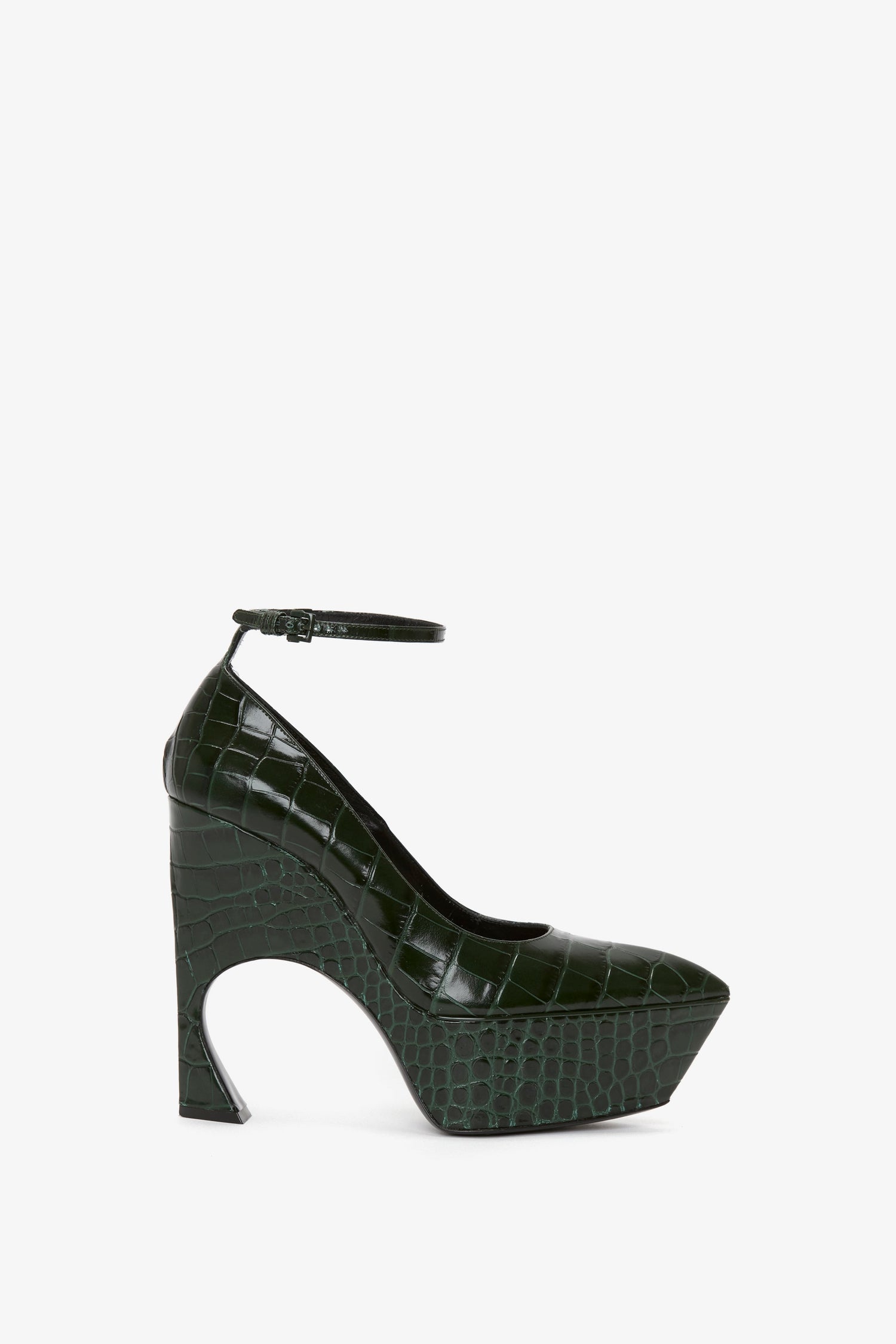 The Ankle Strap Wedge Pump In Dark Green Croc-Effect Leather by Victoria Beckham is a dark green, embossed croc leather pump featuring a chunky, sculptural heel and an adjustable ankle strap.