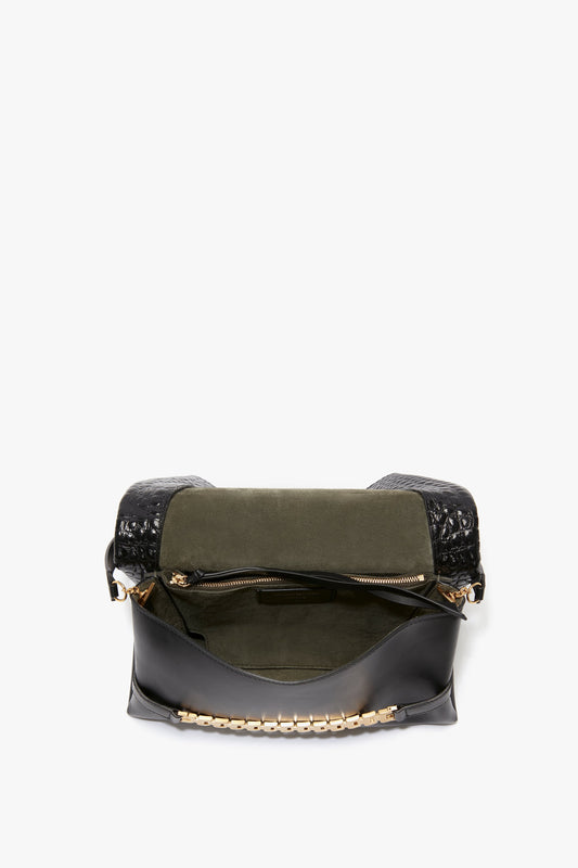 Open the Victoria Beckham Chain Pouch Bag With Strap In Black Croc-Effect Leather, featuring a green interior, crafted from croc embossed leather, with a zippered pocket and a gold chain detail on the front flap.