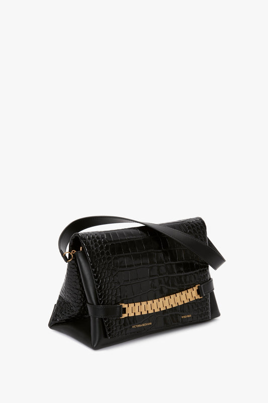 Chain Pouch Bag With Strap In Black Croc-Effect Leather in croc embossed leather with gold-tone hardware, featuring a triangular side profile and a black shoulder strap. This elegant piece is reminiscent of Victoria Beckham's sophisticated style.