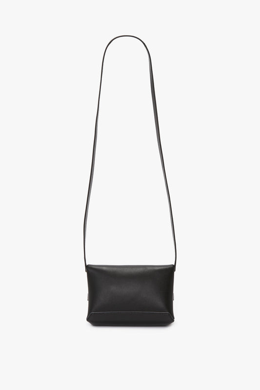 A Mini Chain Pouch Bag With Long Strap In Black Leather crafted from sumptuous black lambskin leather, featuring a long strap, is displayed against a plain white background. The elegant design is by Victoria Beckham.