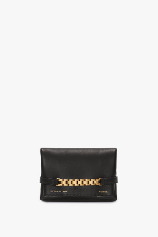 A black lambskin leather clutch bag featuring a gold chain detail and text with "Victoria Beckham" and "H2021" on the front bottom corner, reminiscent of the elegant Mini Chain Pouch Bag With Long Strap In Black Leather by Victoria Beckham.