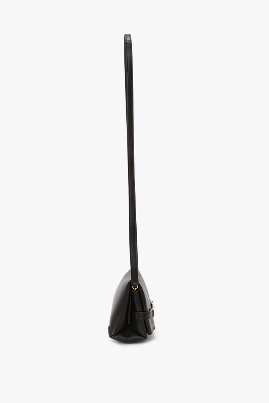 Side view of a Victoria Beckham Mini Chain Pouch Bag With Long Strap In Black Leather with gold-tone hardware, and a structured, triangular shape.