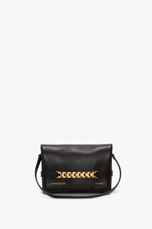 A black leather bag with gold-tone hardware and an adjustable strap is pictured. The classic black bag, known as the "Mini Chain Pouch Bag In Black Leather," features the text "Victoria Beckham" and "Peyton.