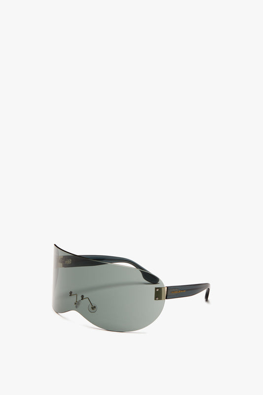 A pair of sleek, green-tinted Oversized Shield Sunglasses with dark temple arms and a minimalistic design featuring grey smoke nylon lenses and the signature Victoria Beckham logo, set against a plain white background.